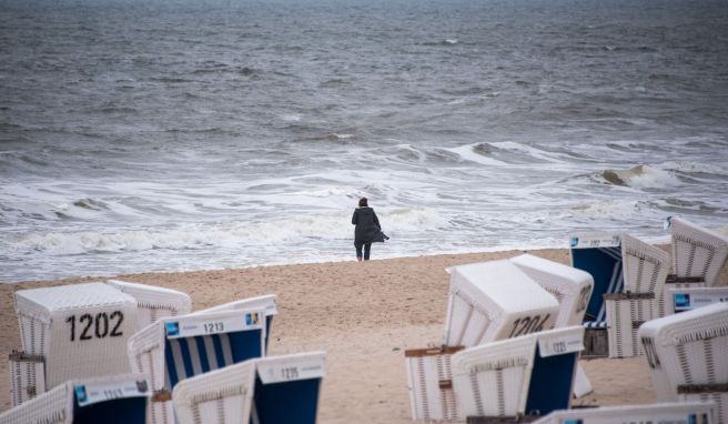 Eine Frau spaziert auf der Nordseeinsel am sehr leeren Strand in Westerland entlang. Das Leben für die Einheimischen ist nicht immer einfach.