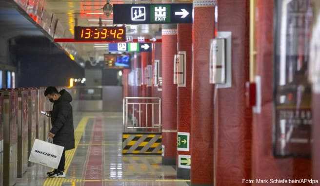 Ein Mann mit Mundschutz wartet an einer U-Bahn-Station auf einen Zug - China-Reisende müssen infolge des Coronavirus mit erheblichen Einschränkungen der Mobilität rechnen